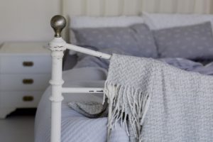a blanket draped over the end of a metal bed frame