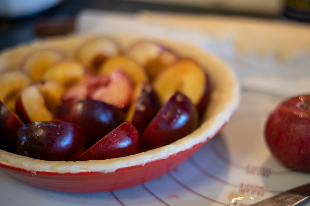 plum halves arranged in an uncooked pie crust